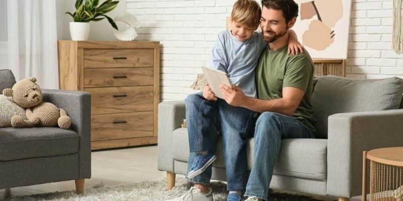 a father and son sitting on a couch in a living room