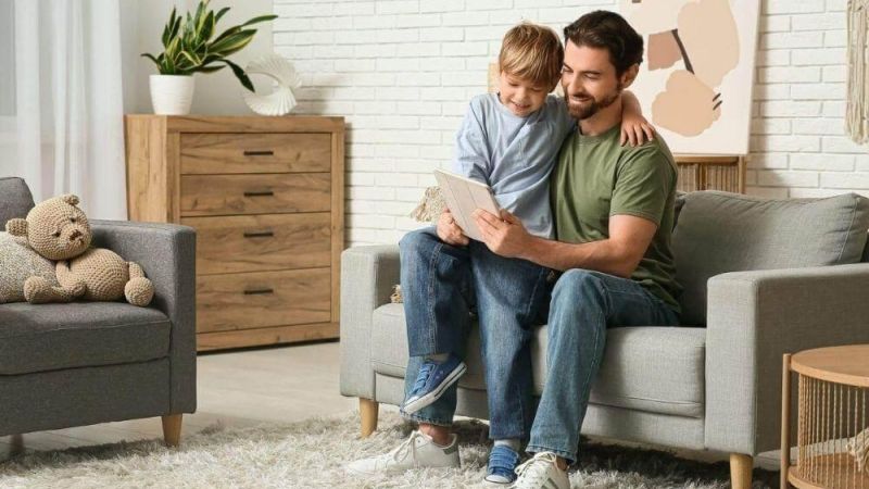 a father and son sitting on a couch in a living room