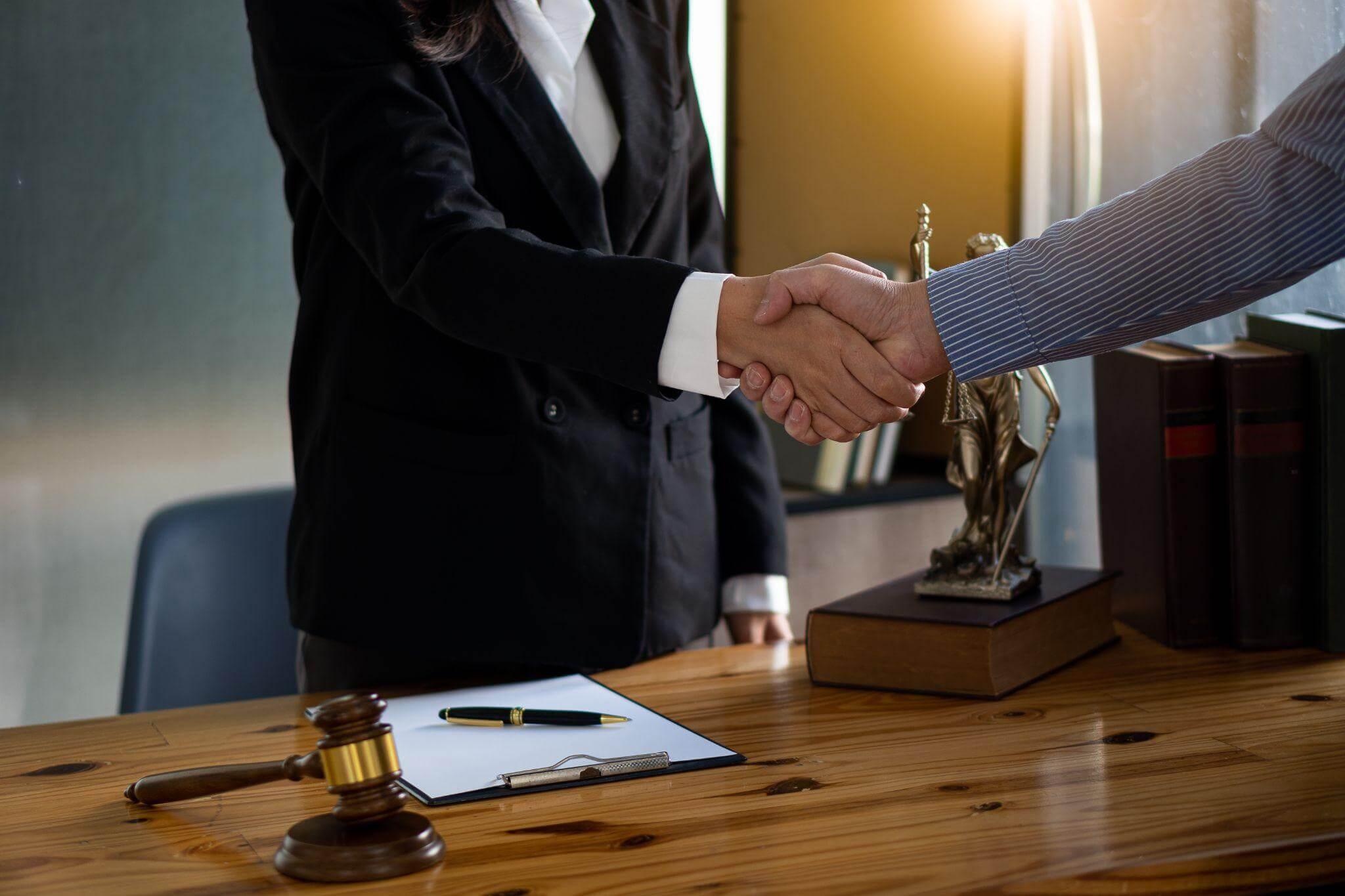 Couple shaking hands over a desk, perhaps a